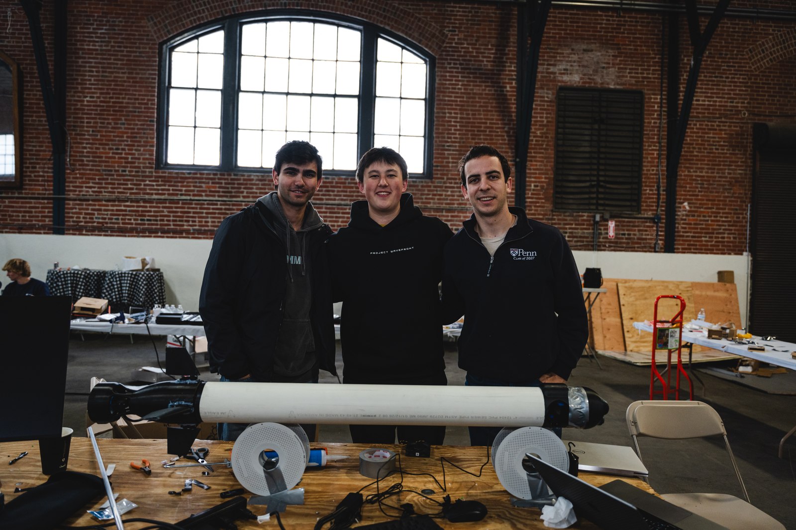 Three team members standing behind the finished vehicle at the hackathon
